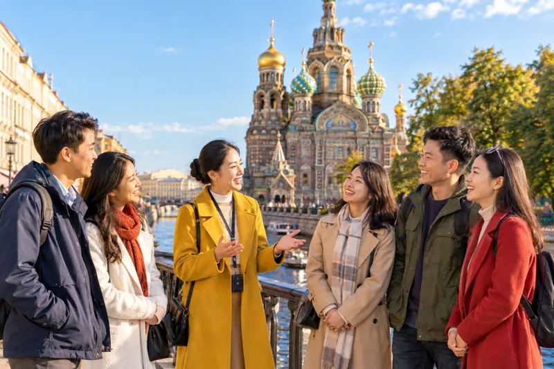 Hướng dẫn viên người Việt áo vàng trò chuyện với nhóm khách bên kênh ở St. Petersburg